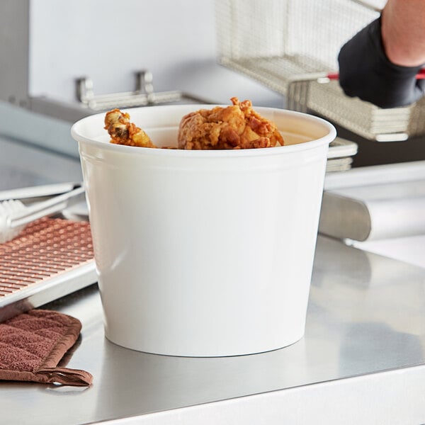 A person holding an Innopak white food bucket filled with fried chicken.