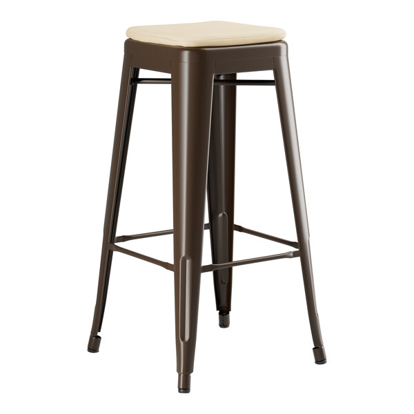 A brown metal Lancaster Table & Seating outdoor backless bar stool with a tan cushion.