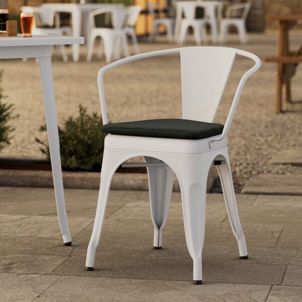 A Lancaster Table & Seating white outdoor arm chair with a black cushion.
