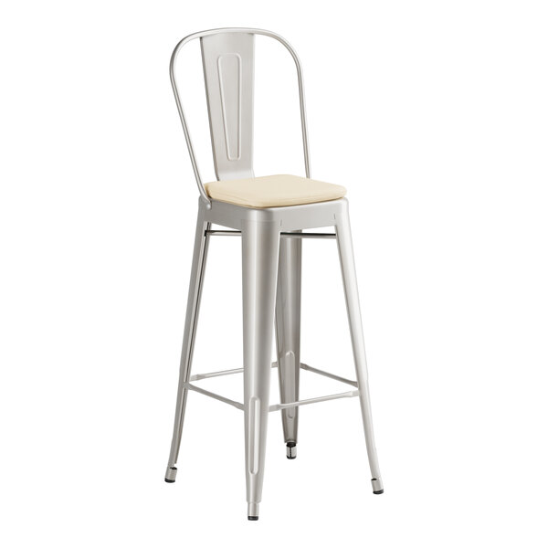A Lancaster Table & Seating silver metal bar stool with a tan cushion.