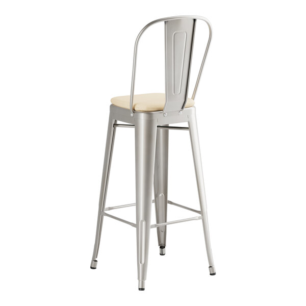 A Lancaster Table & Seating metal barstool with a tan cushion.