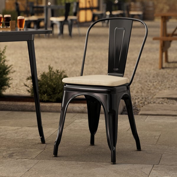 A Lancaster Table & Seating Onyx Black Outdoor Cafe Chair with a tan cushion on it.