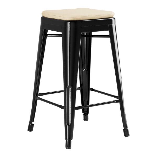 A Lancaster Table & Seating black metal backless outdoor restaurant bar stool with a tan cushion on the seat.
