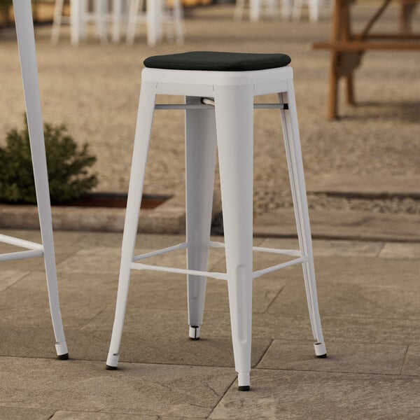 A white Lancaster Table & Seating outdoor bar stool with a black cushion.