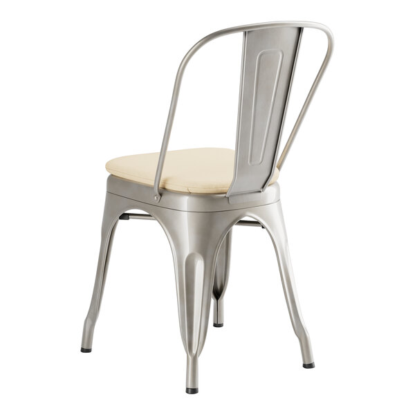 A Lancaster Table & Seating metal chair with a tan cushion.