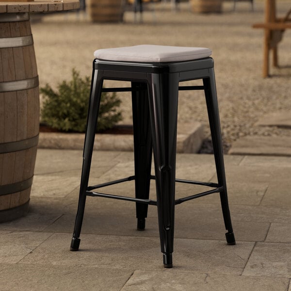 A Lancaster Table & Seating black outdoor backless counter height stool with a gray cushion on top.