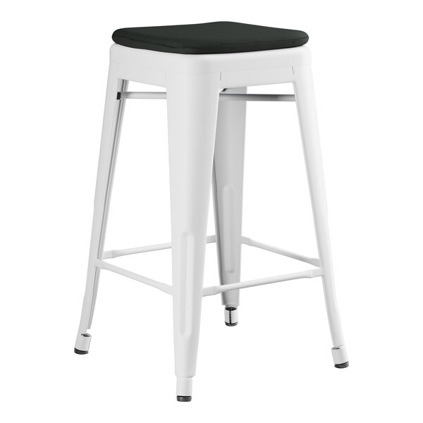 A white metal Lancaster Table & Seating outdoor backless counter height stool with a black cushion.