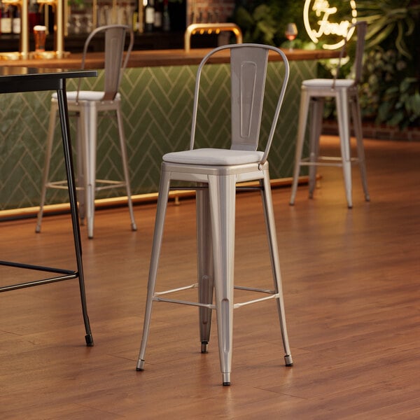 A Lancaster Table & Seating silver metal barstool with a gray fabric cushion.