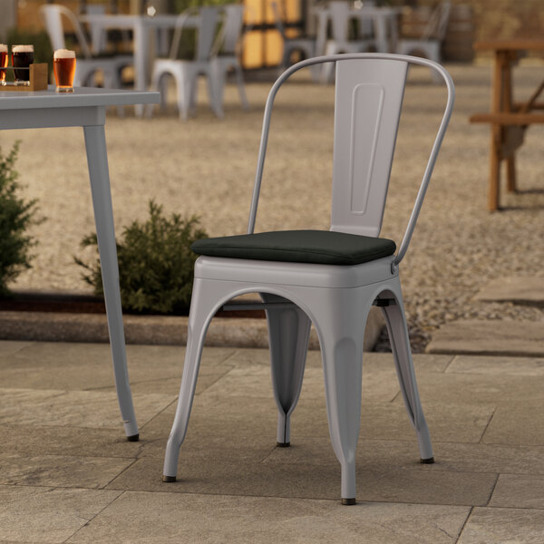 A Lancaster Table & Seating gray metal outdoor cafe chair with a black cushion.