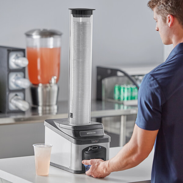 A man using a KleanTake by ServSense gravity fed tube to dispense a cold lid.