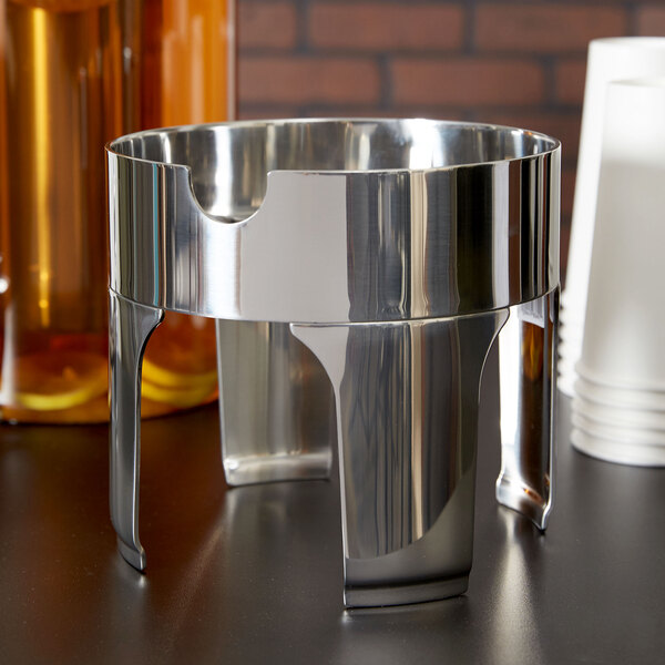 A stainless steel base for a Vollrath New York 2 gallon beverage dispenser on a counter.