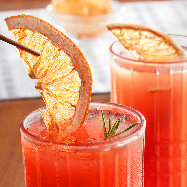 Two glasses of orange juice with a dried grapefruit slice on top.