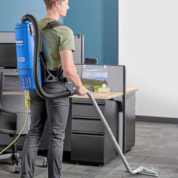A man with a Clarke backpack vacuum cleaner on his back.
