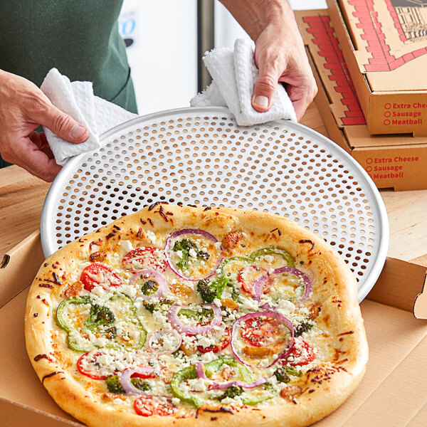 An American Metalcraft 13" Heavy Duty Aluminum Perforated Pizza Screen with a pizza on it.