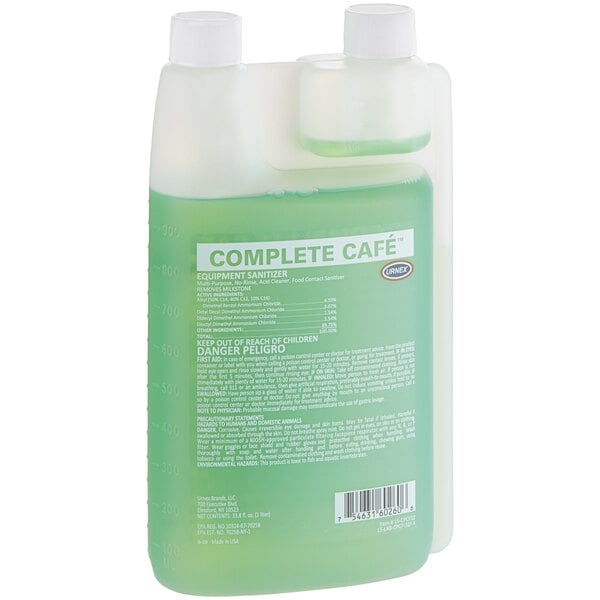 A plastic container of Urnex Complete Cafe Coffee Equipment Sanitizer, filled with green liquid.