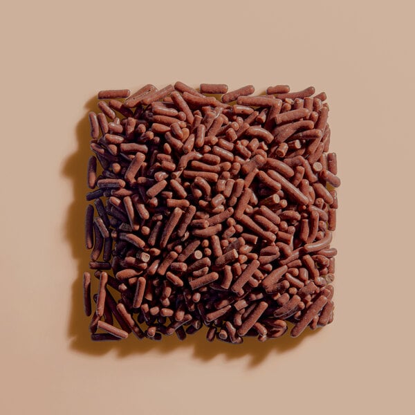 A pile of chocolate sprinkles arranged in a square shape on a neutral background.