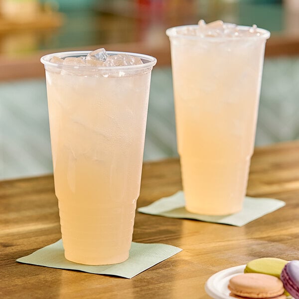 Two Choice clear plastic cups of liquid with ice on napkins.