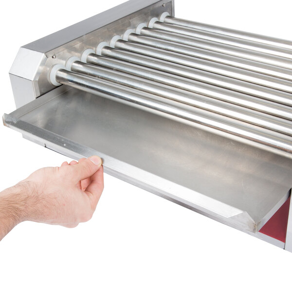 A hand using a Carnival King Drip Tray on a metal roller.