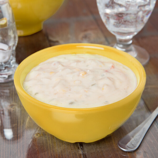 A close up of a yellow bowl of food on a table.