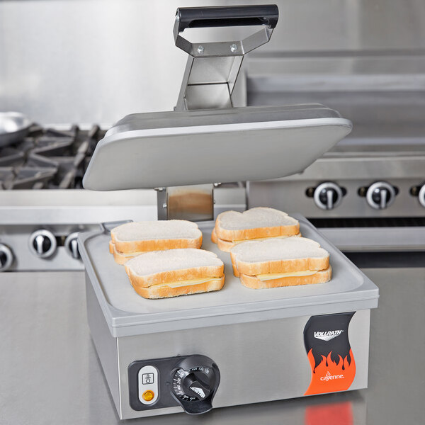 A Vollrath panini grill with several sandwiches on it.