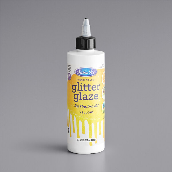 A close up of a white Satin Ice bottle with a yellow label for Yellow Vanilla Glitter Glaze.