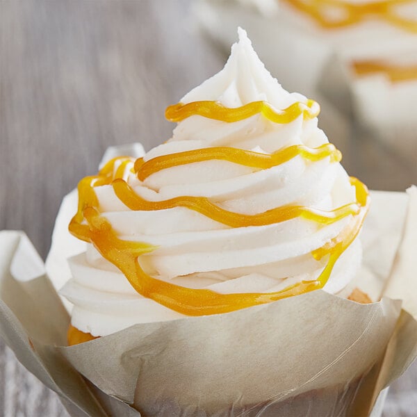 A cupcake with white frosting and yellow glitter on top.