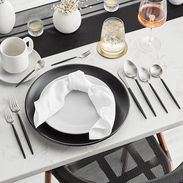 A table set with black and silver Acopa Odin dinner forks and white plates.
