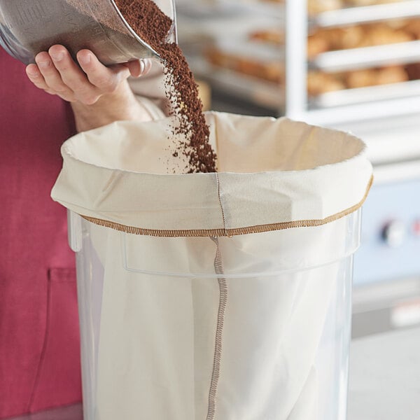 A woman using a CoffeeSock Cold Brew reusable coffee filter to pour coffee into a metal container.