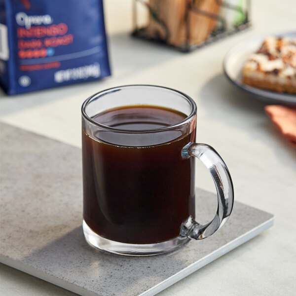 A glass mug of Lavazza Intenso ground coffee on a table.