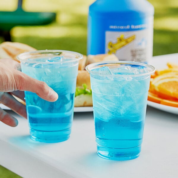 A person holding a glass of Sqwincher mixed berry electrolyte beverage concentrate.