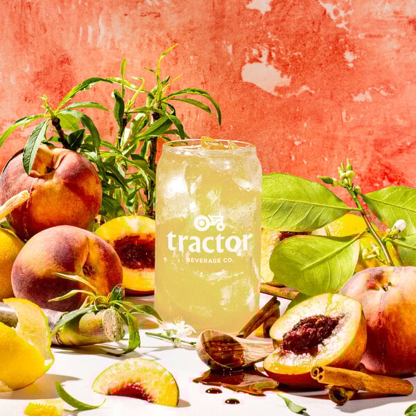 A glass of Tractor Beverage Co. peach juice concentrate with a drink next to peaches.