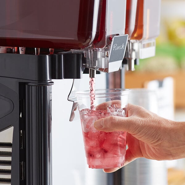 A hand pouring Tractor Beverage Co. Farmer's Punch into a glass.