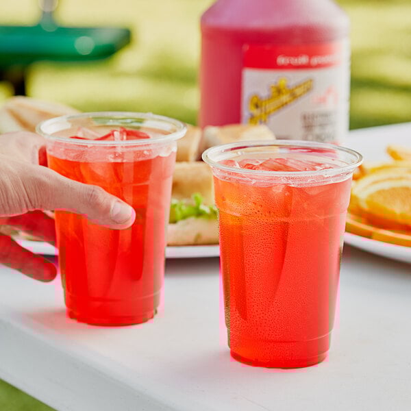 A hand holding a plastic cup with Sqwincher Fruit Punch.