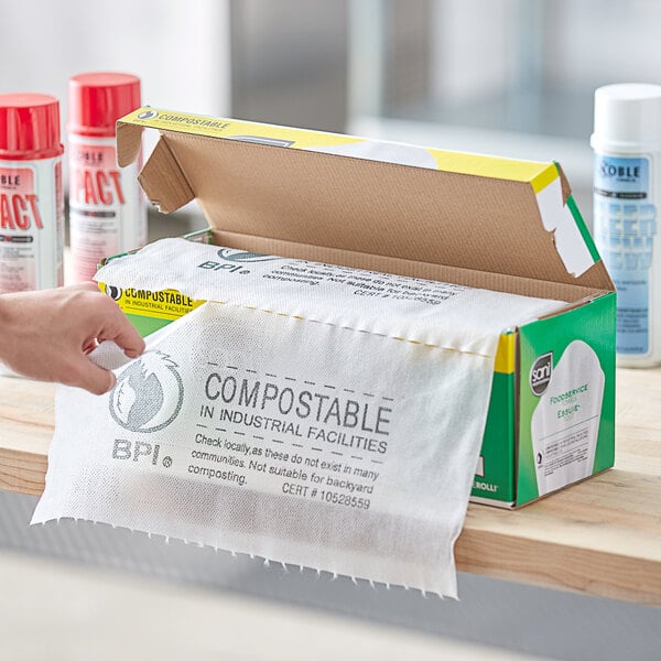 A hand putting a Sani Professional Perforated Foodservice Towel into a box.