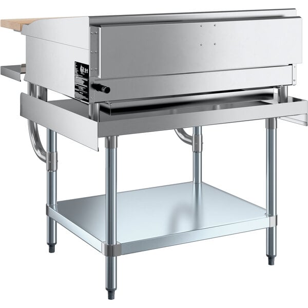 A large stainless steel Cooking Performance Group manual griddle on a wooden counter with a stainless steel plate shelf.