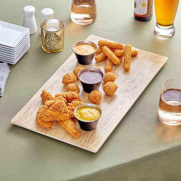 An Acopa faux wood melamine serving board with fried chicken, fries, and sauce on it.