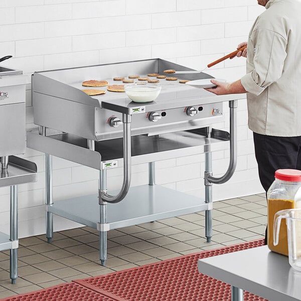 A man cooking food on a Cooking Performance Group manual griddle.