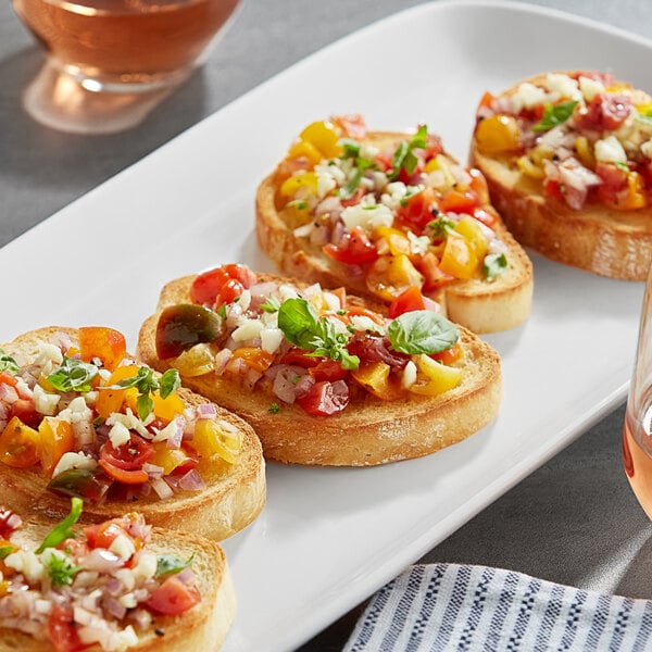 Sliced Turano Pane Bruschetta Bread topped with tomatoes and cheese on a white plate on a table in a brunch café.