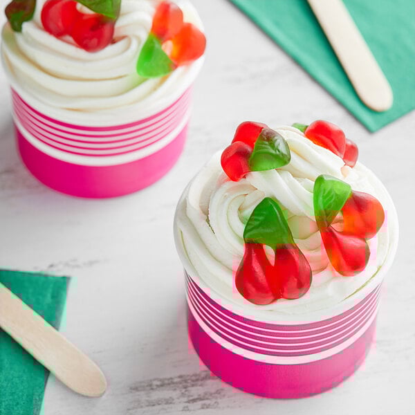 Two cupcakes with cherry and strawberry decorations on top.