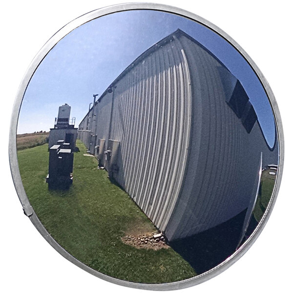 A circular Vestil outdoor convex mirror with a reflection of a building.