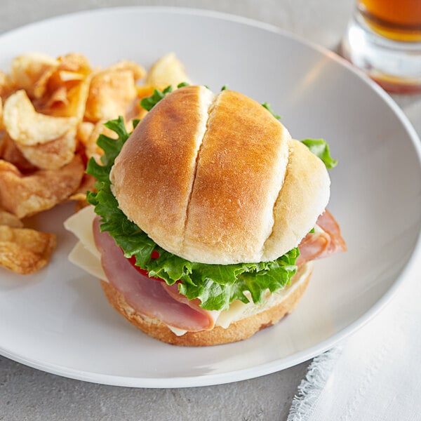 A sandwich with meat, lettuce, and cheese on a Turano Gourmet Sandwich Roll on a plate.