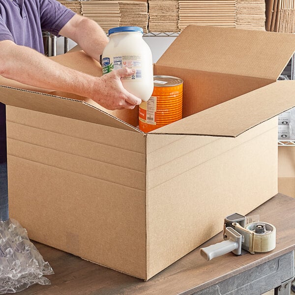 A man packing a cardboard box with a jug of milk and canned food.