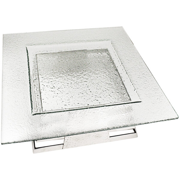 A Spring USA square tempered glass plate set on a glass table with a metal base.