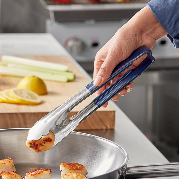 A person using Vollrath Jacob's Pride tongs to pick up scallops.