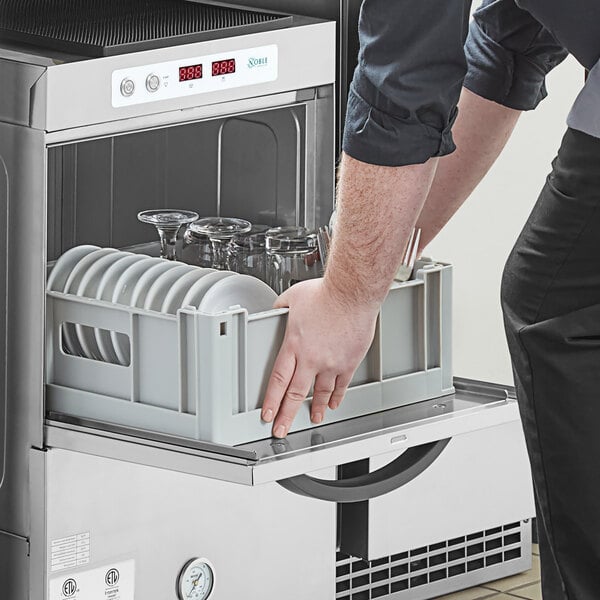 A man using a Noble Warewashing flat rack to load glasses in a dishwasher.