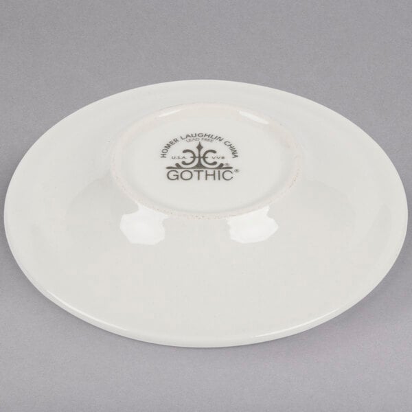 An ivory Homer Laughlin undecorated saucer with black text.