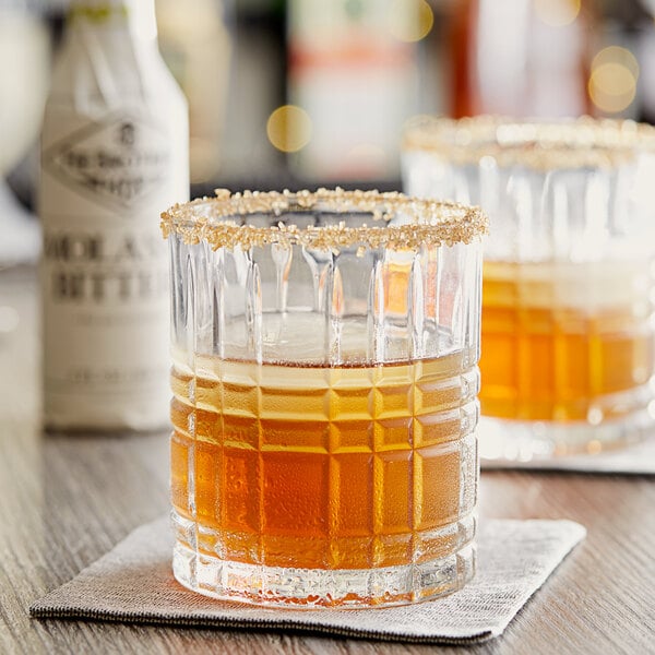 Two glasses of brown liquid with Fee Brothers Molasses Bitters on a table.