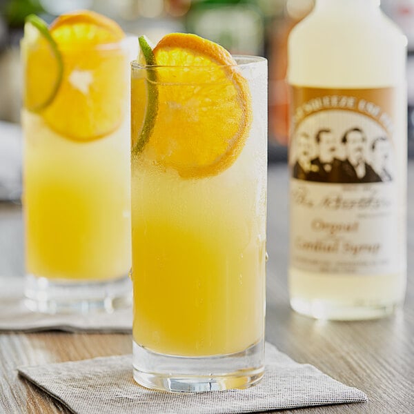 A glass of yellow liquid with orange slices on top.
