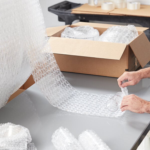 A man using Pregis medium bubble wrap to pack a product.