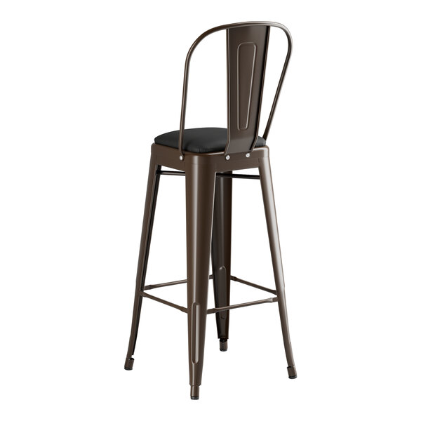 A brown metal Lancaster Table & Seating bar stool with a black cushion.